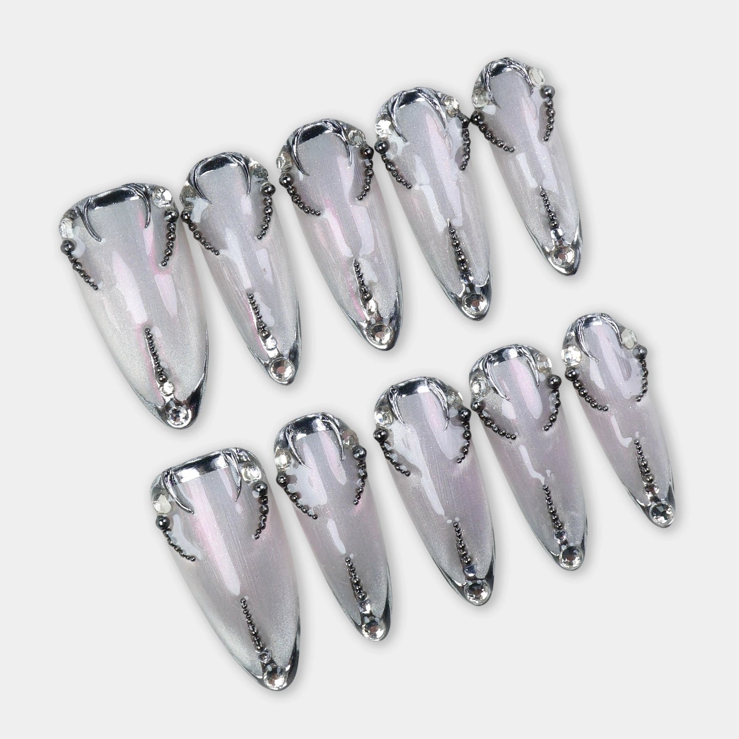 Shimmery silver press-on nails outlined with black chrome details and tiny beaded chains forming a symmetrical design.