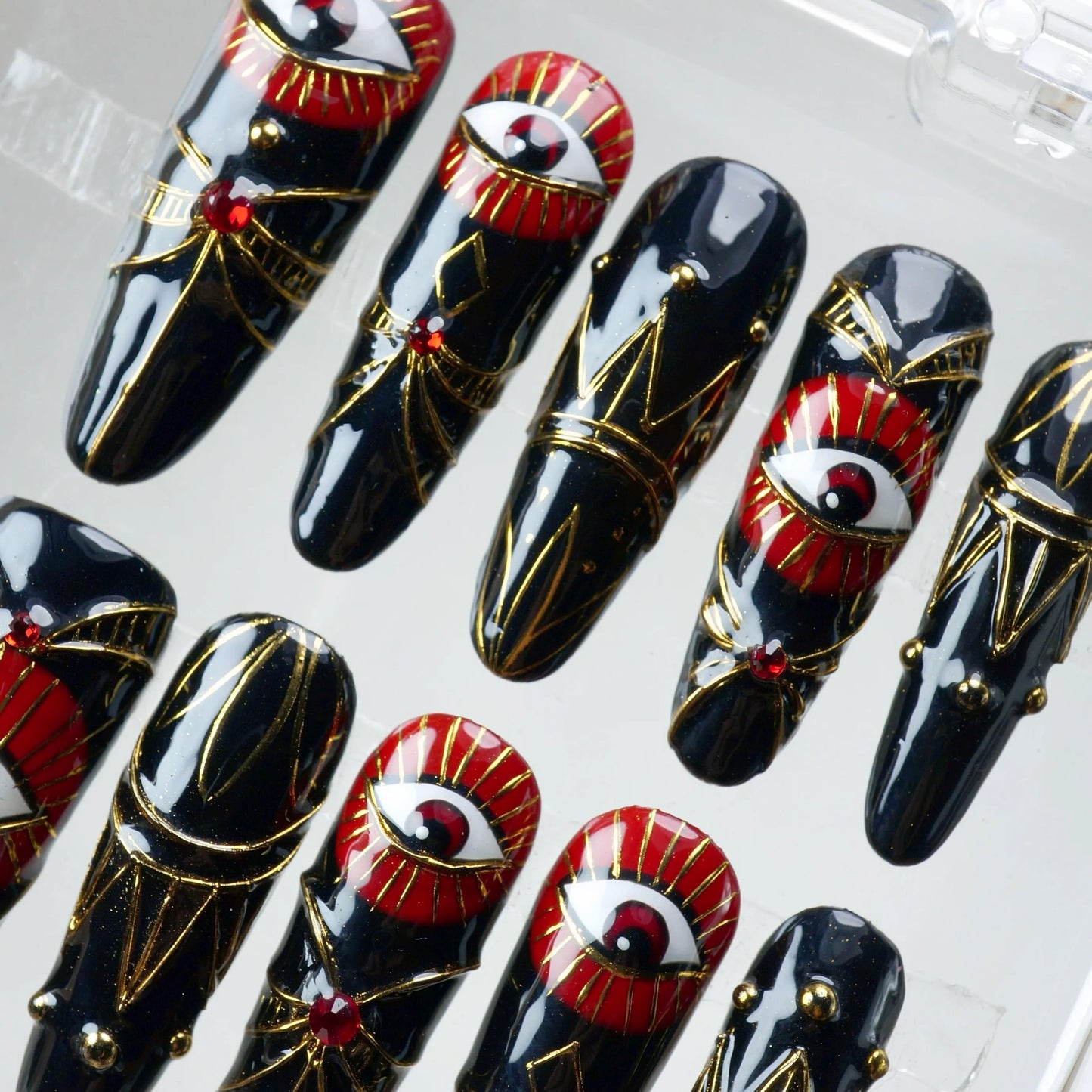 Eye-catching press-on nails with red-and-gold mystical eye art and luxurious metallic accents, handmade by Donailsart