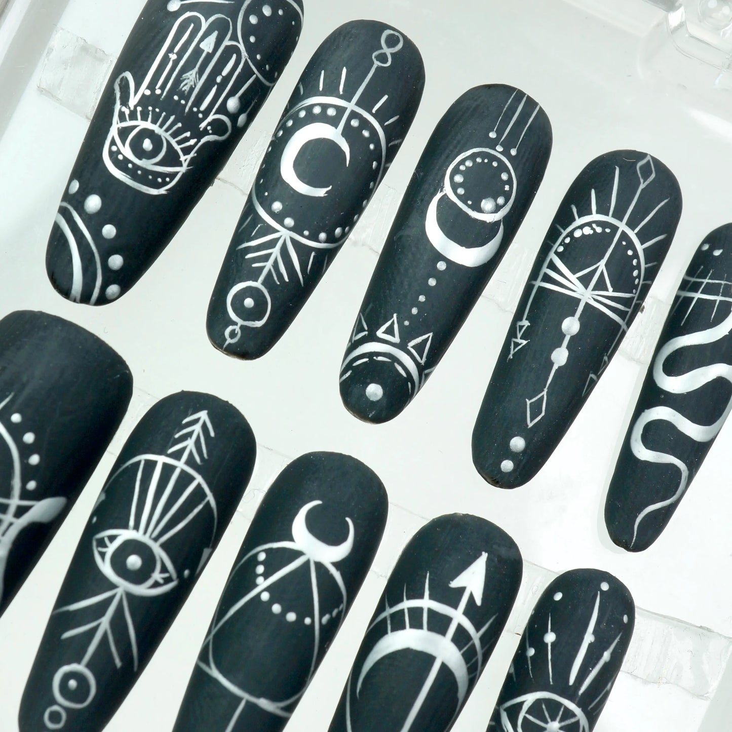Donailsart press-on nails with spiritual iconography such as hamsa hands, cosmic arrows, and sacred geometry in monochrome style