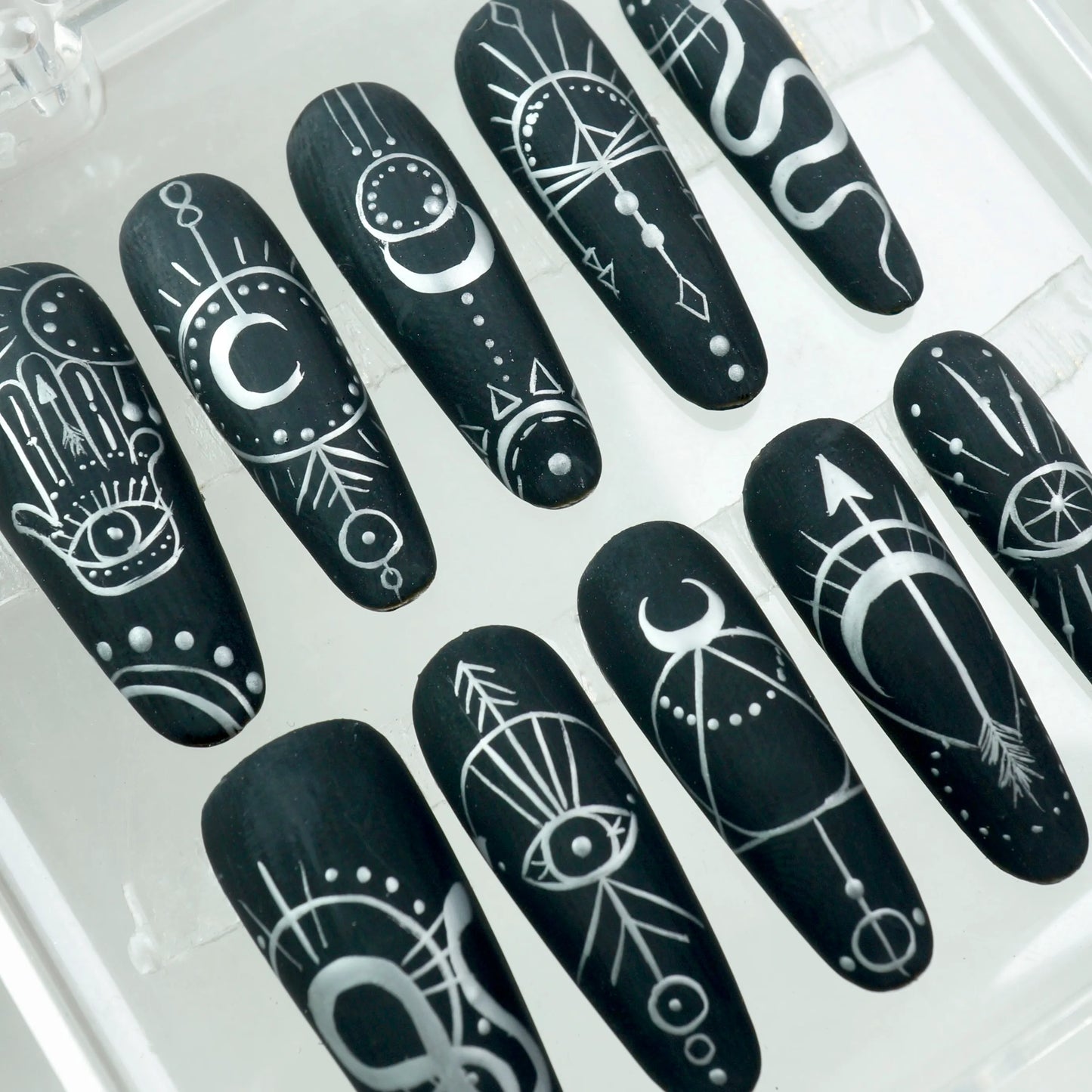 Mystic black press-on nails with fine white occult linework and celestial symbols
