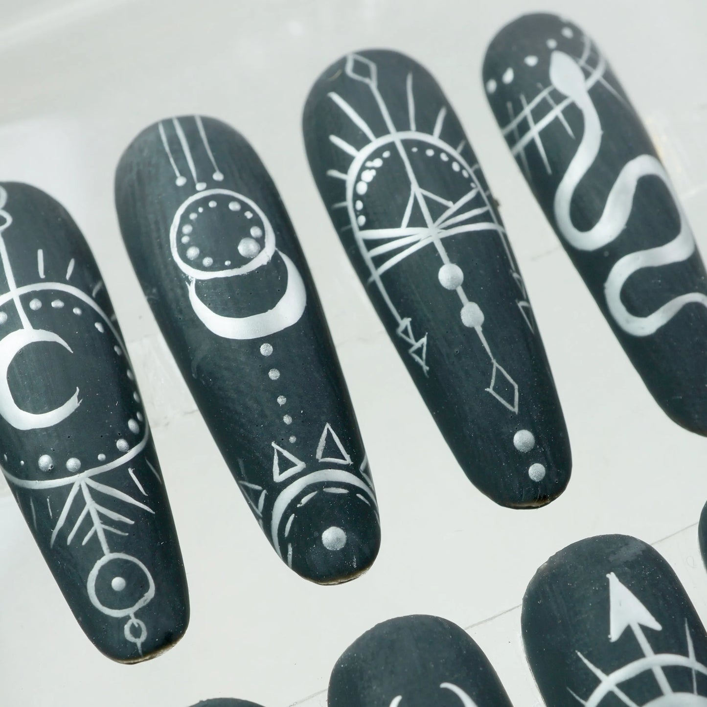 Press-on nails from Donailsart with striking matte black base and white astrology-inspired graphics, perfect for spiritual souls