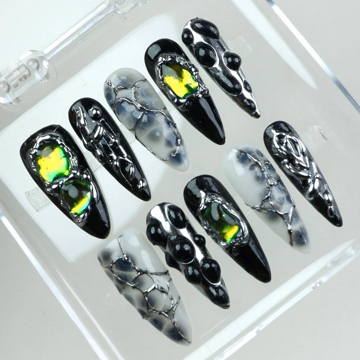 Alien-core meets high fashion—these press-on nails blend shattered glass effects, liquid chrome, and holographic stones in a dark palette.