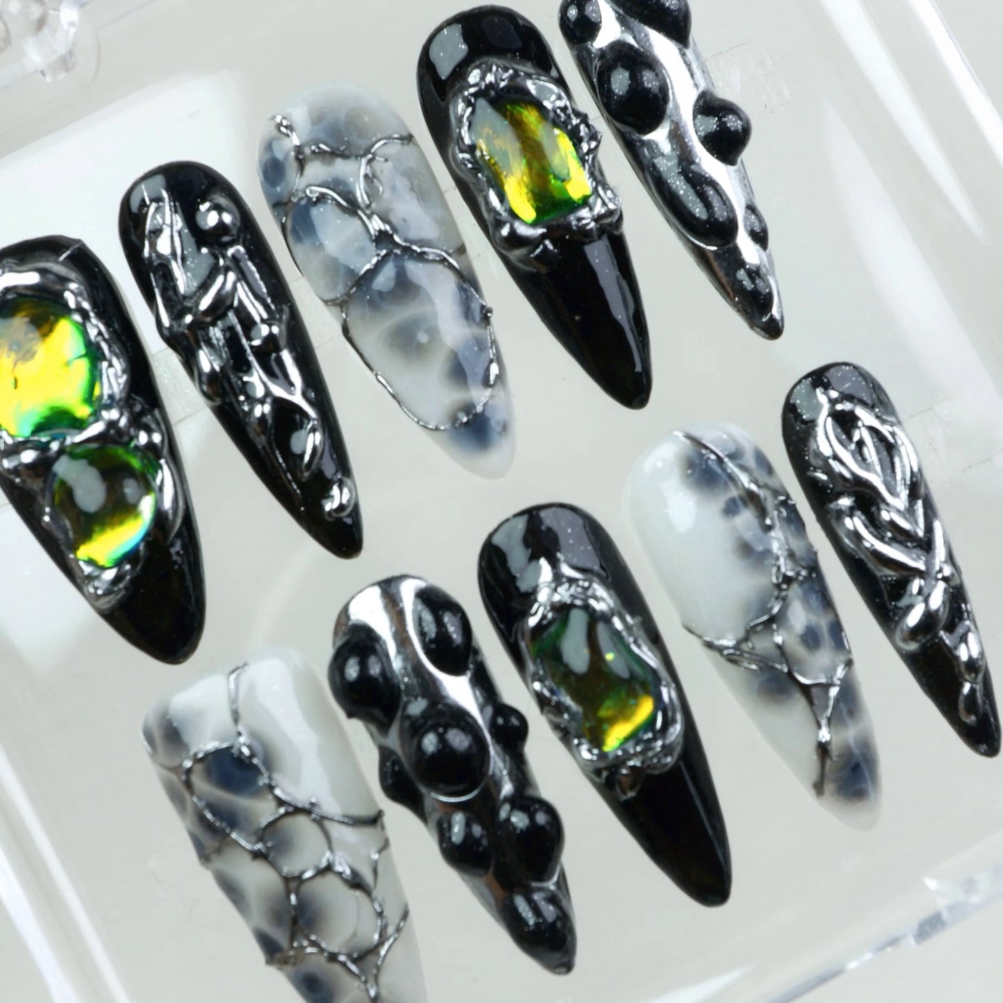 Alien-core meets high fashion—these press-on nails blend shattered glass effects, liquid chrome, and holographic stones in a dark palette.