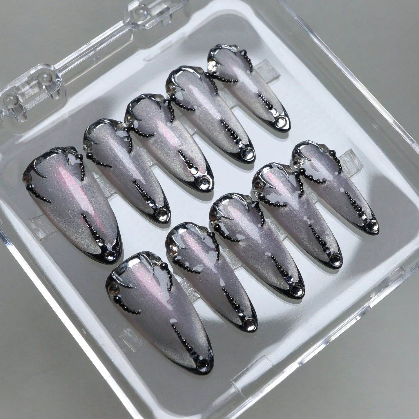 Chrome silver press-on nails with black gothic accents and delicate dot patterns for a sleek futuristic look.