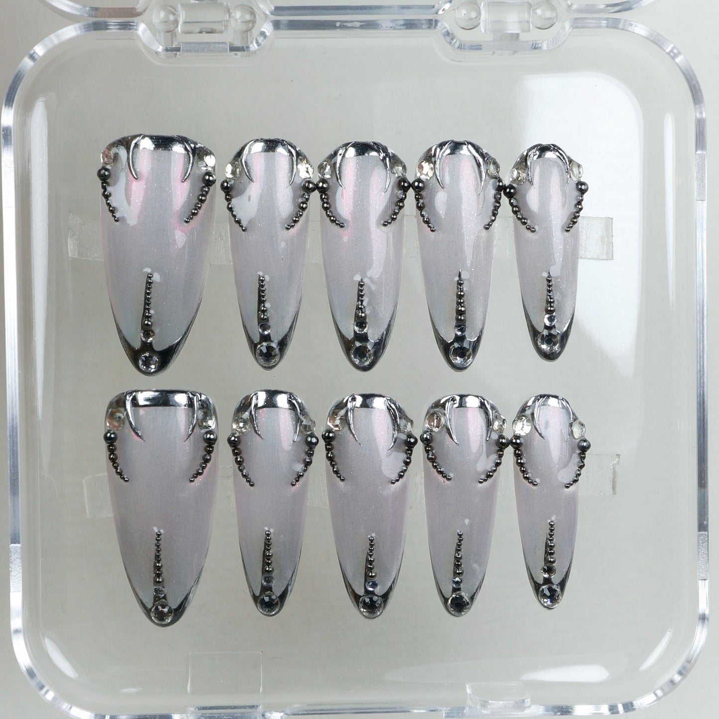 Pearl-silver press-on nails with sculpted black chrome tips and a dotted spine – classy with a dark twist.