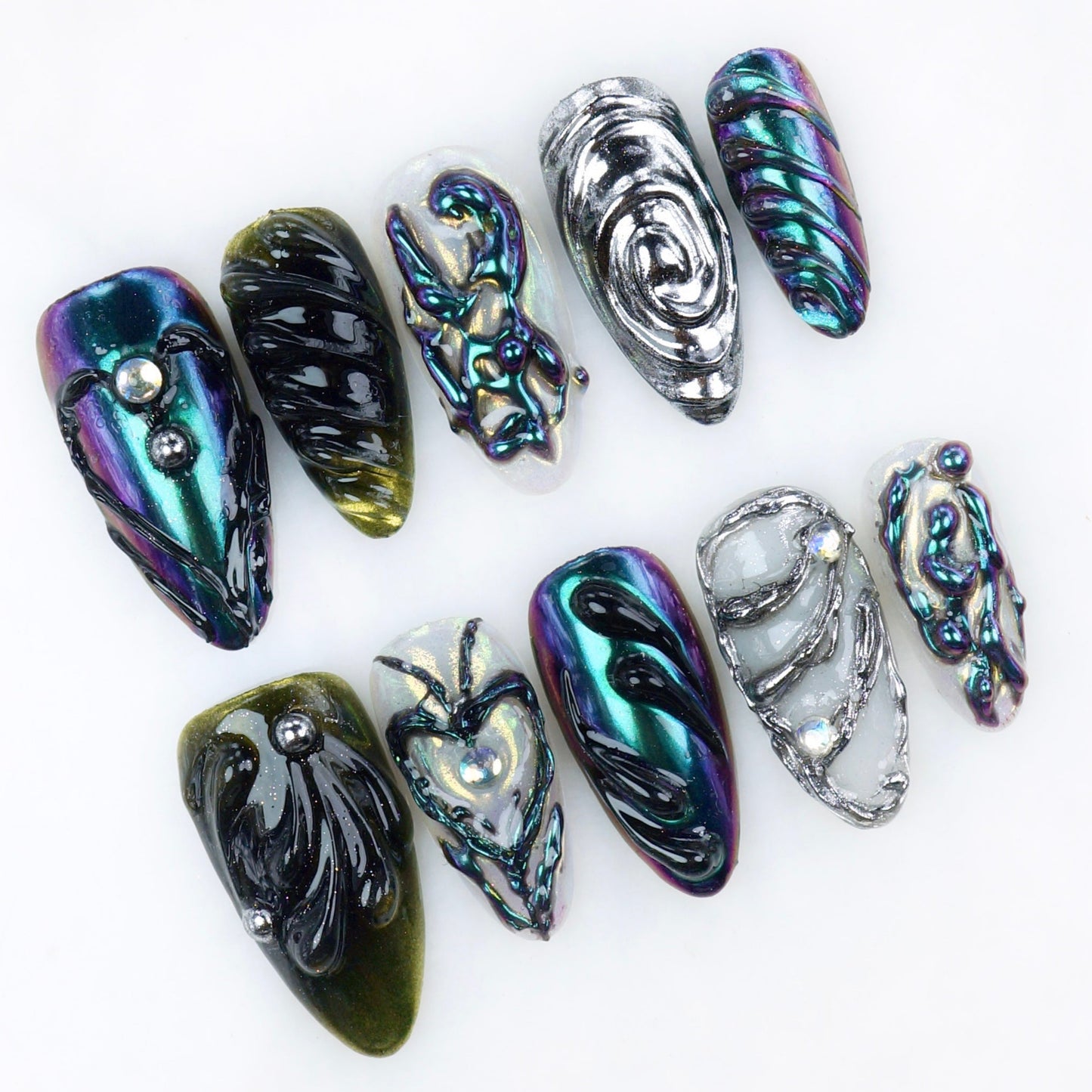 Glossy chrome press-on nails in dark iridescent tones with sculpted 3D textures, abstract swirls, and metallic details.
