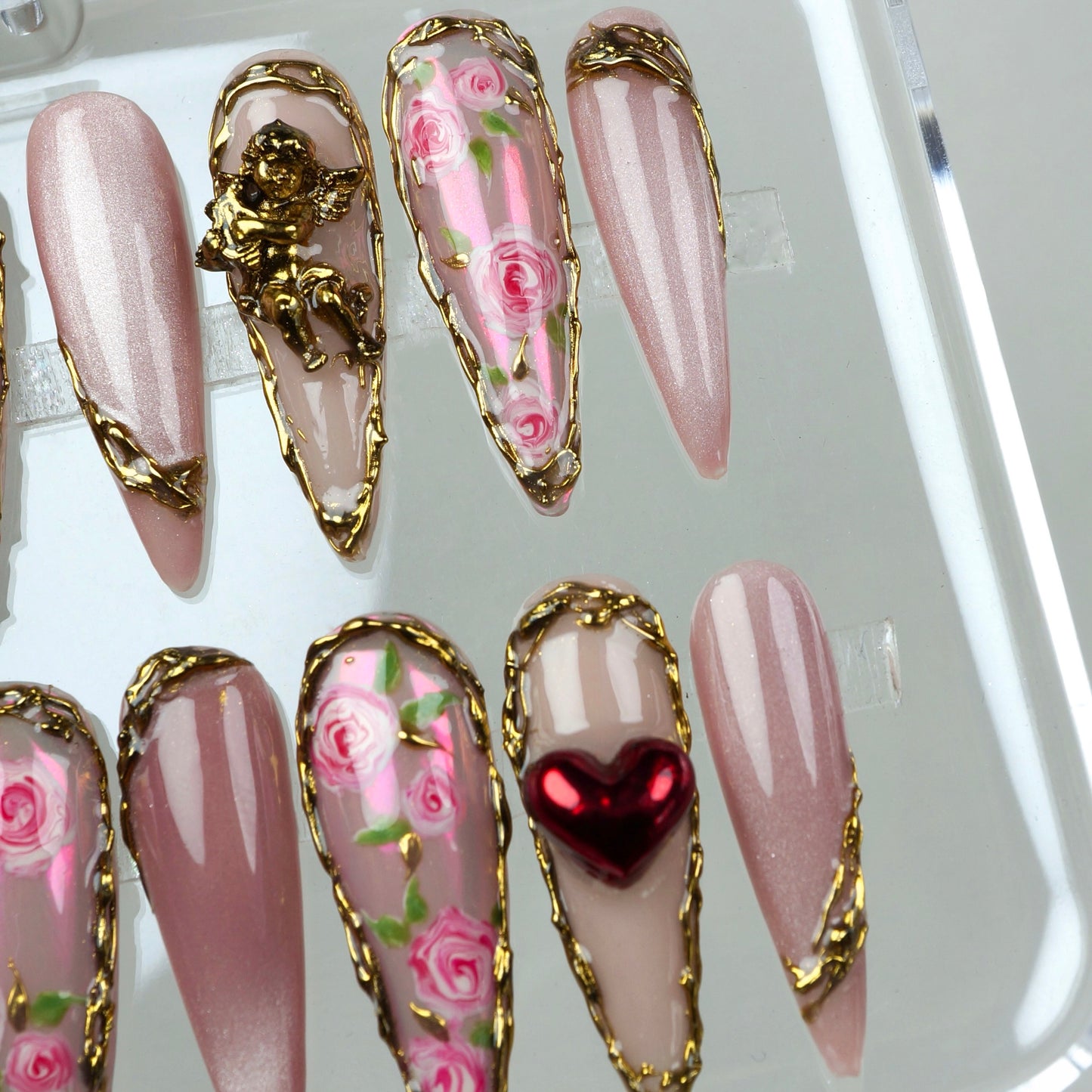 Soft pink nails with mini rose gardens, golden borders, and love-themed 3D charms perfect for Valentine’s vibes.
