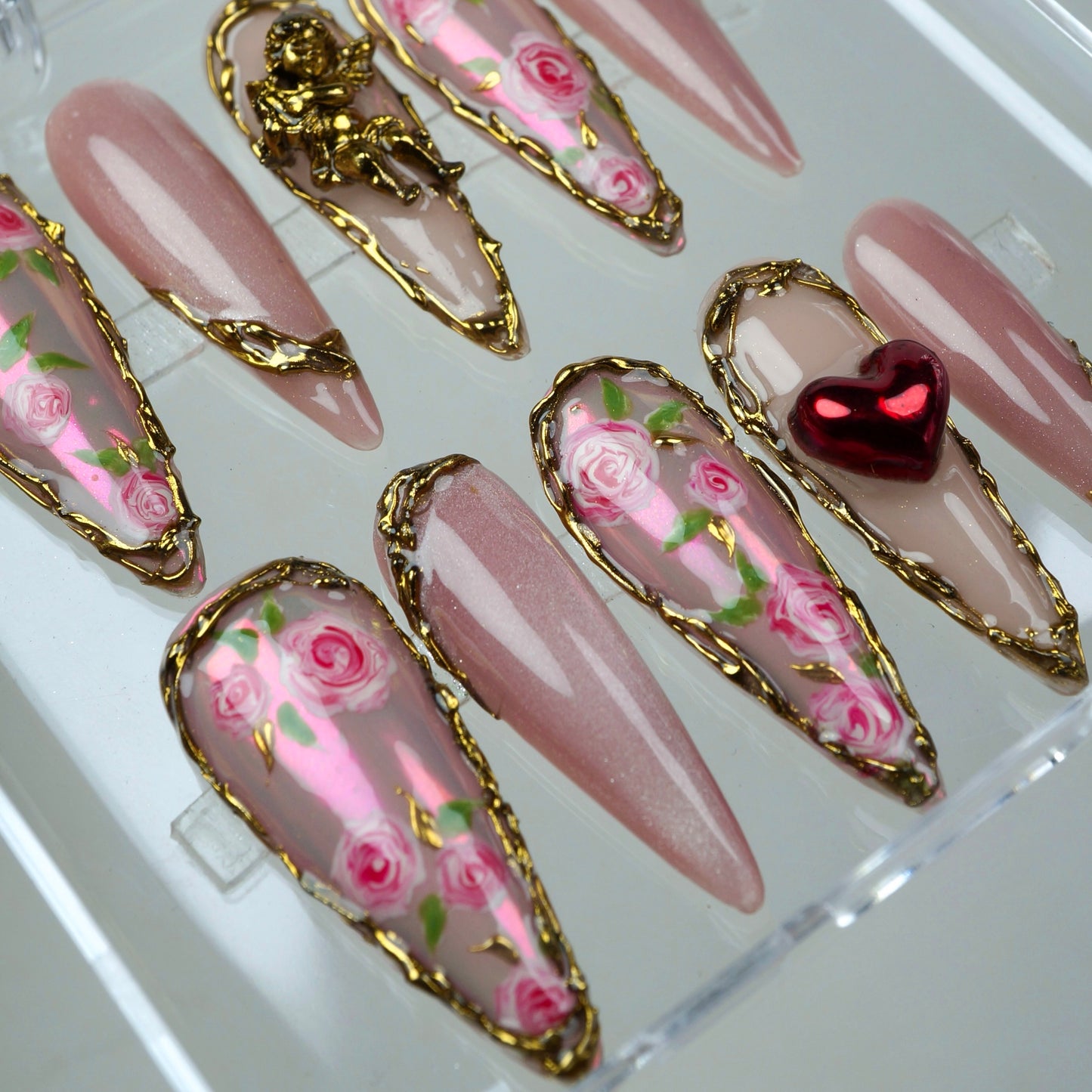 Soft pink nails with mini rose gardens, golden borders, and love-themed 3D charms perfect for Valentine’s vibes.