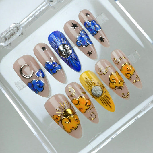 Celestial press-on nails with 3D moon and sun details, blue and gold clouds, and starry night accents.