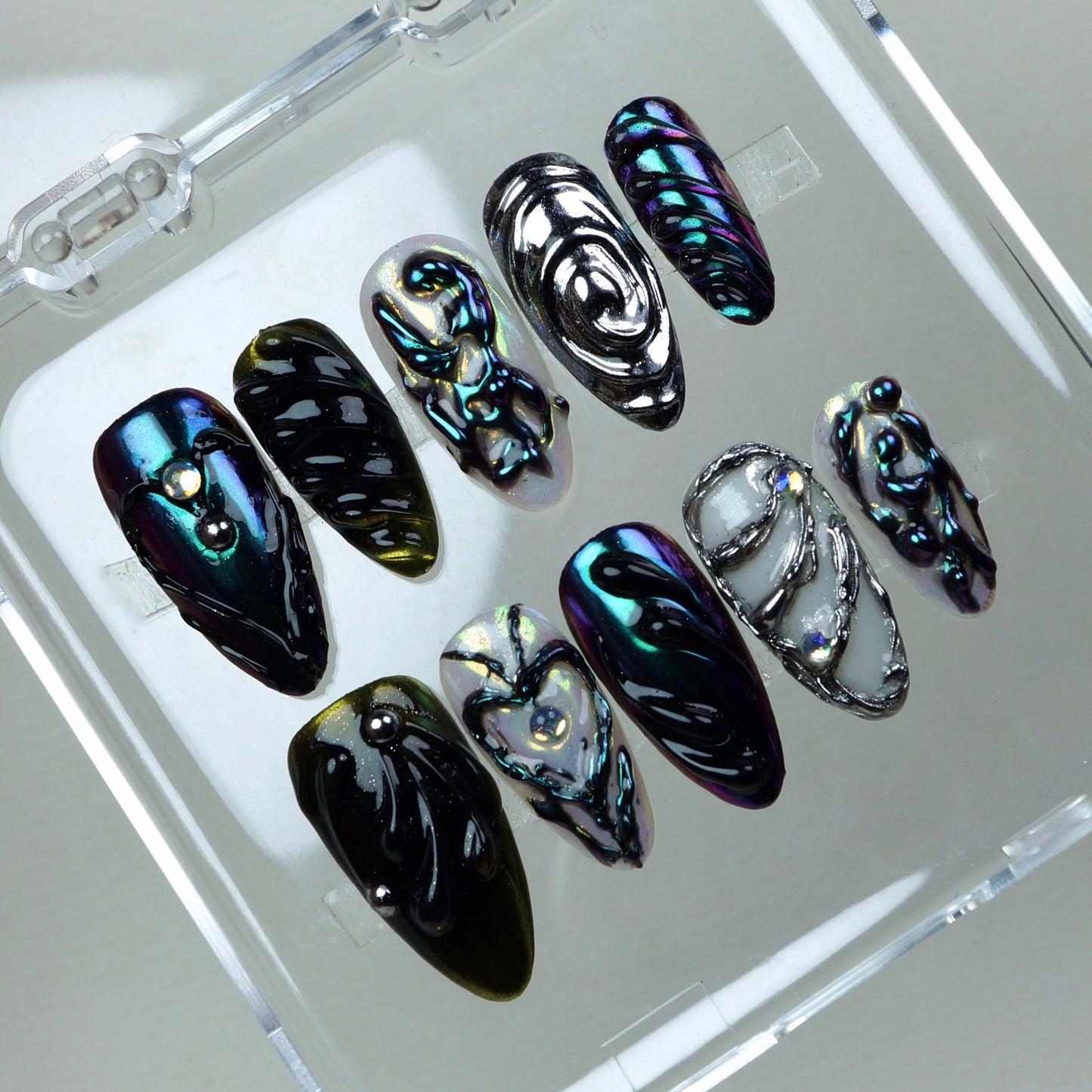 Galactic-inspired press-on nails featuring multichrome finishes, jelly-like swirls, and futuristic silver accents.