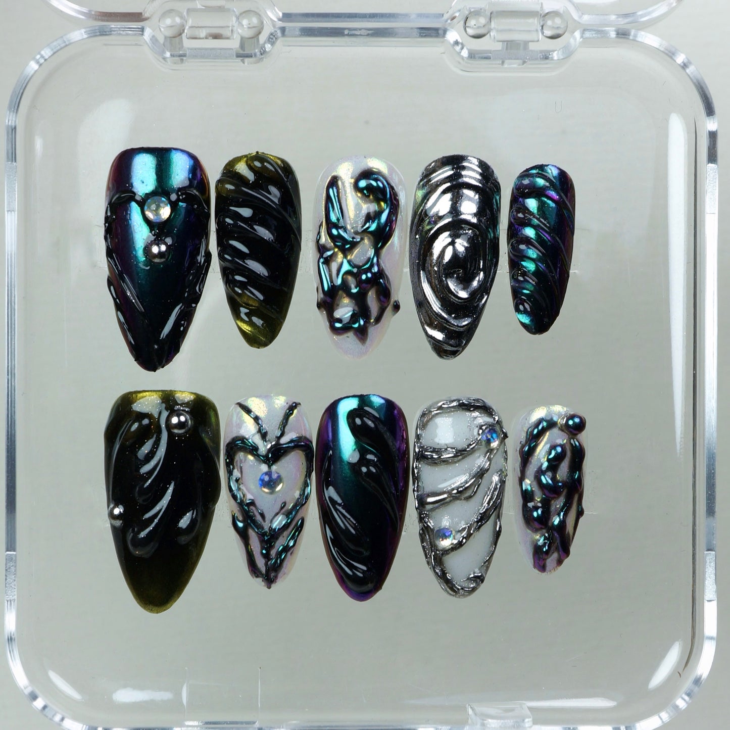 Avant-garde press-on nail set with reflective color shifts, fluid 3D forms, and intricate textural patterns.