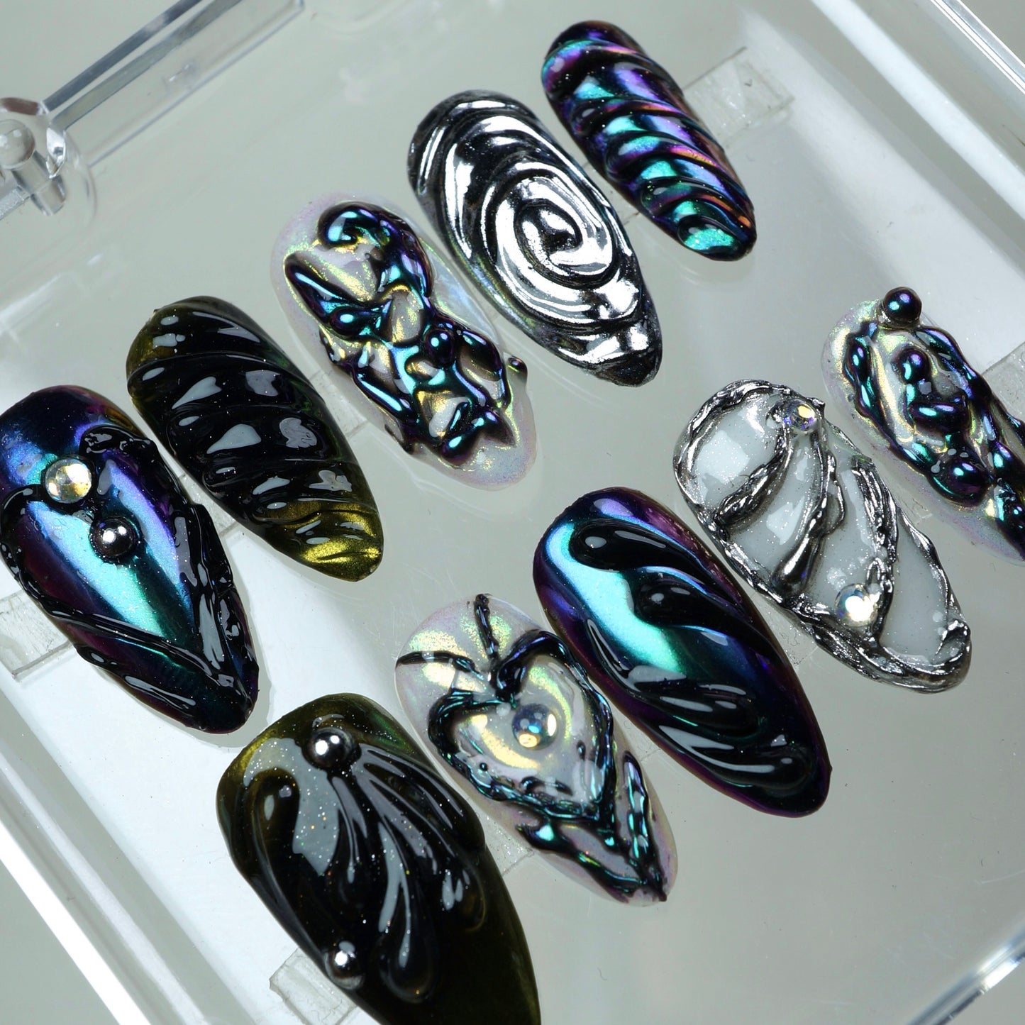 Galactic-inspired press-on nails featuring multichrome finishes, jelly-like swirls, and futuristic silver accents.