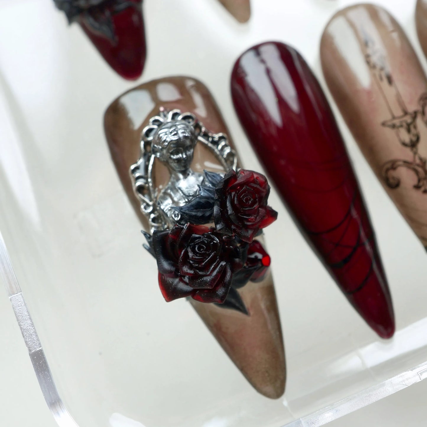 Gothic nails in deep wine and smoky nude tones with black rose art, metallic angels, and candle motifs – by Donailsart.