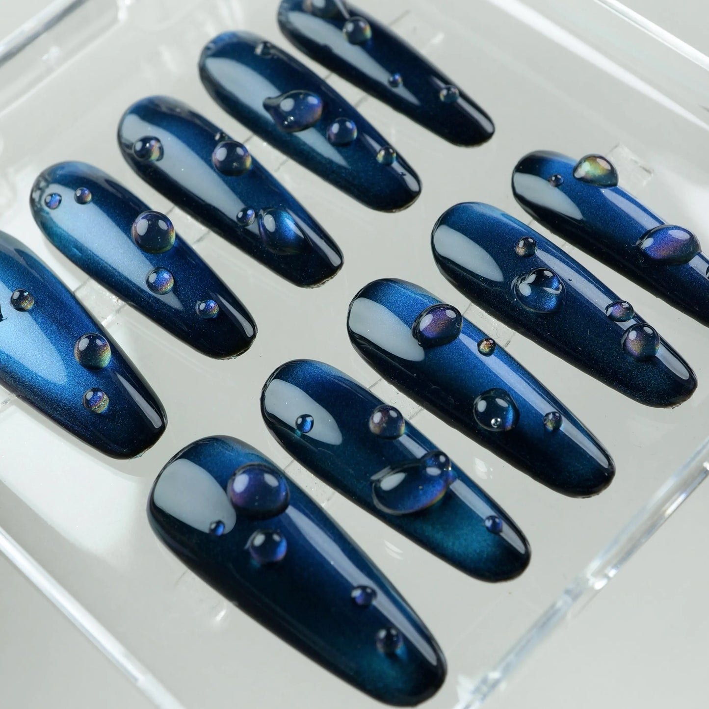 Elegant navy cat eye gel nails featuring depth-enhancing shimmer and glossy bubble-like droplets