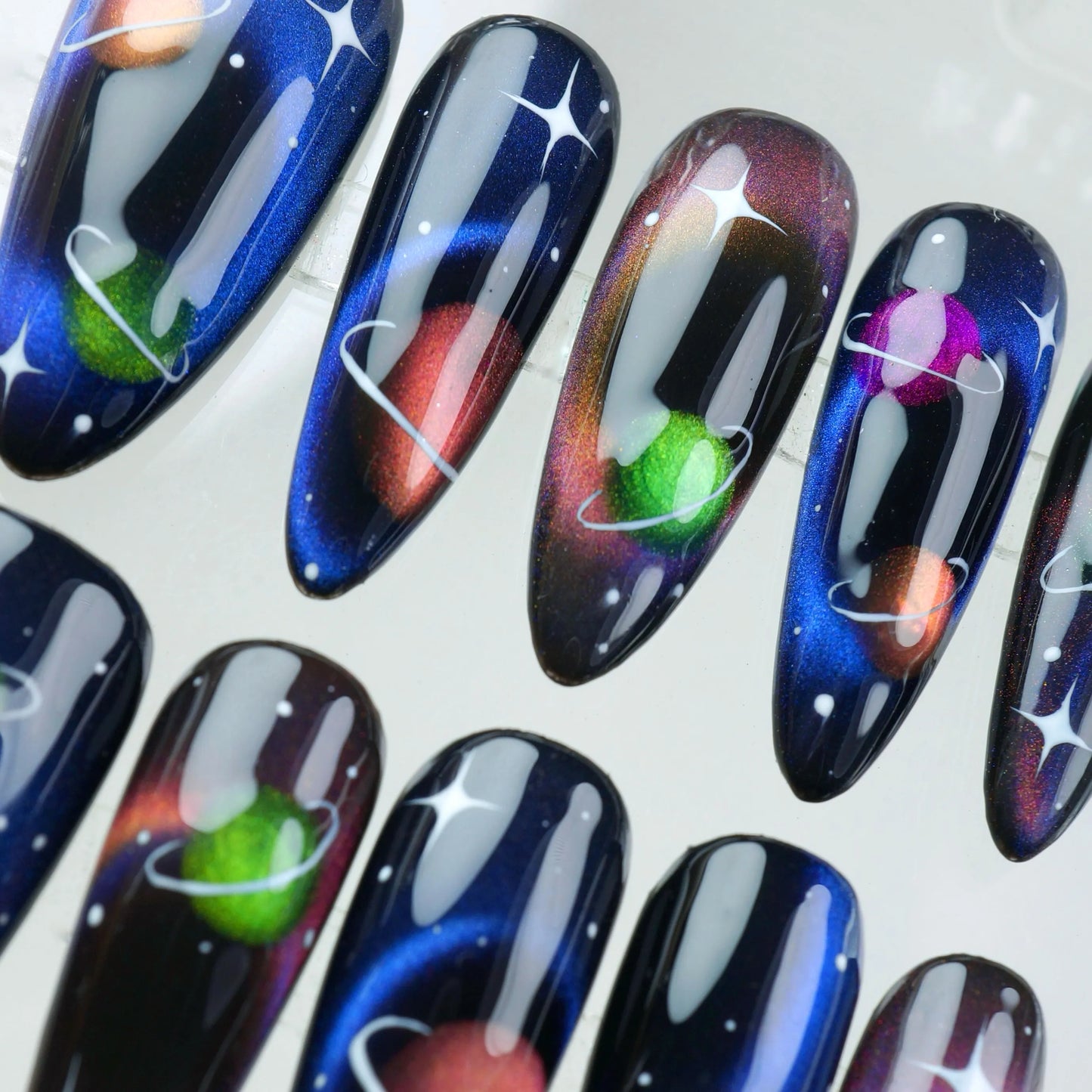 Space-inspired press-on nails with multicolor planet designs, deep space ombré, and stardust sparkle
