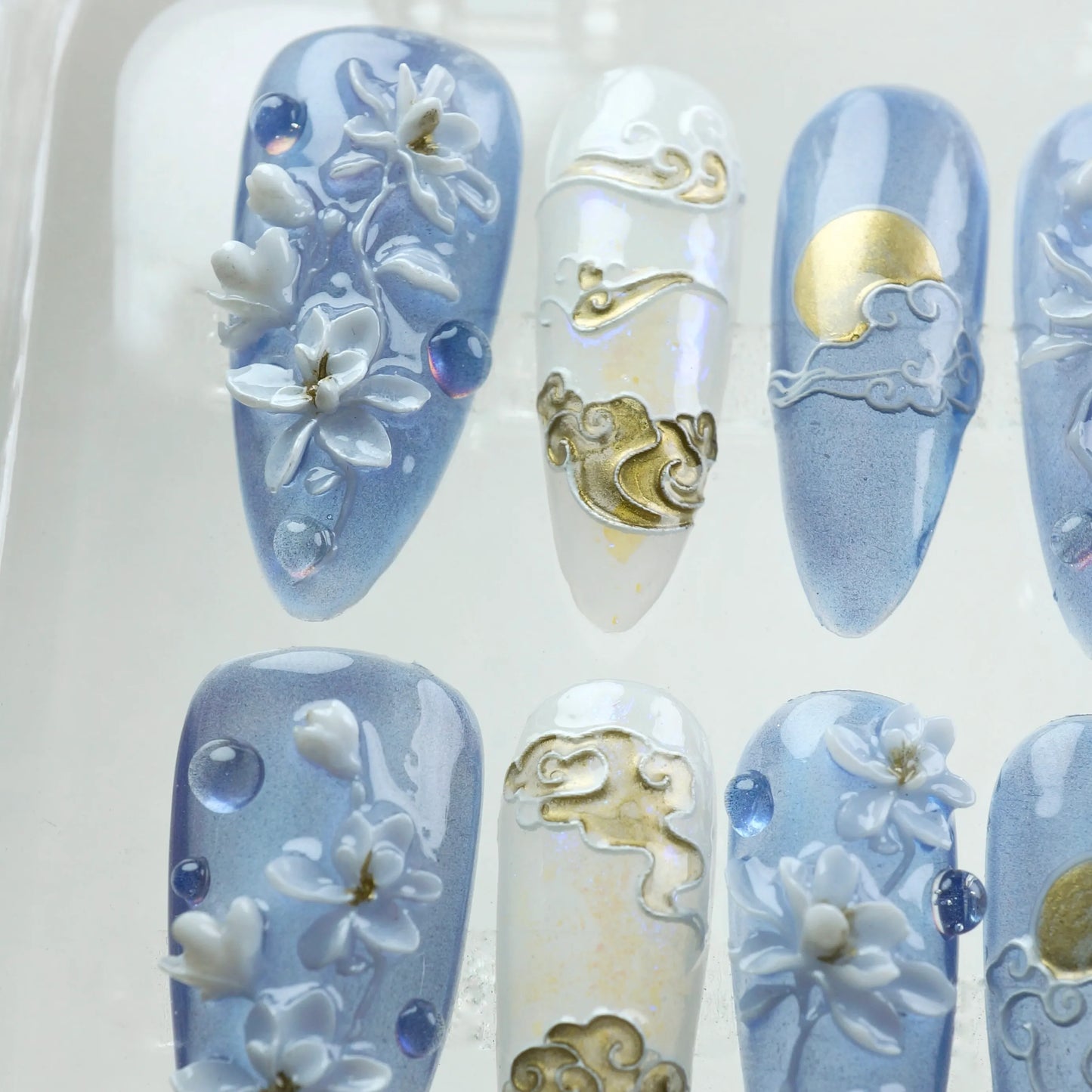 Elegant press-on nails inspired by Asian art, with sculpted flowers, gold scroll patterns, and moonlight gradients