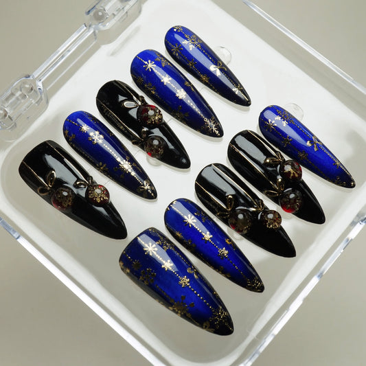 Holiday nail set featuring deep blue shimmer, black glossy tips, and gold snowflake art with jewel charms Donailsart
