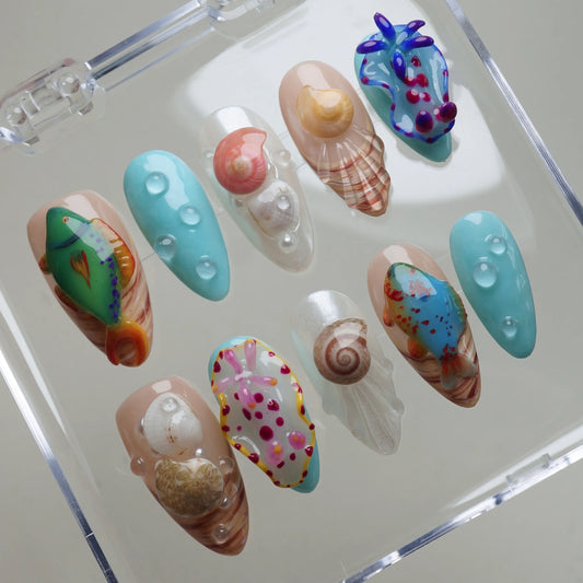 Seaside Trinkets press-on nails on a clear display stand showing the full aquarium-inspired nail art collection – Donailsart