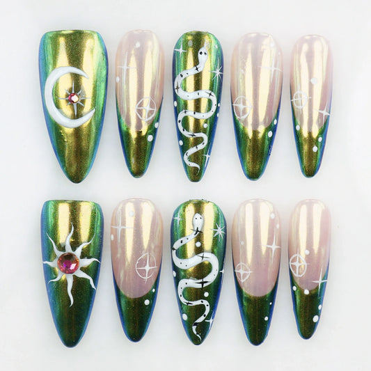 Mystic Moonlit handcrafted press-on nails flat lay – green and nude chrome stiletto set with moon, sun, snake and star celestial symbols by Do.nails