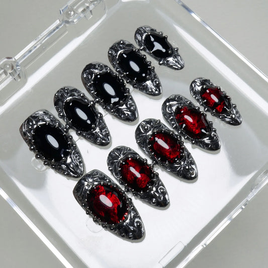 Elegant press-on nails featuring deep red and black glassy stones set in ornate silver baroque detailing