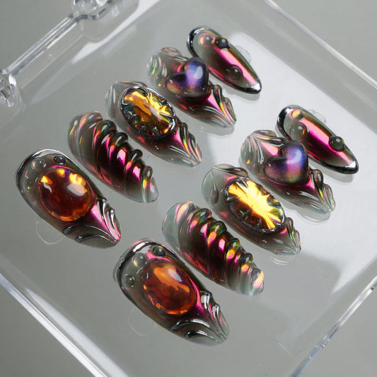 Iridescent press-on nails by Donailsart featuring metallic finishes, 3D heart and gem details, and a futuristic aesthetic