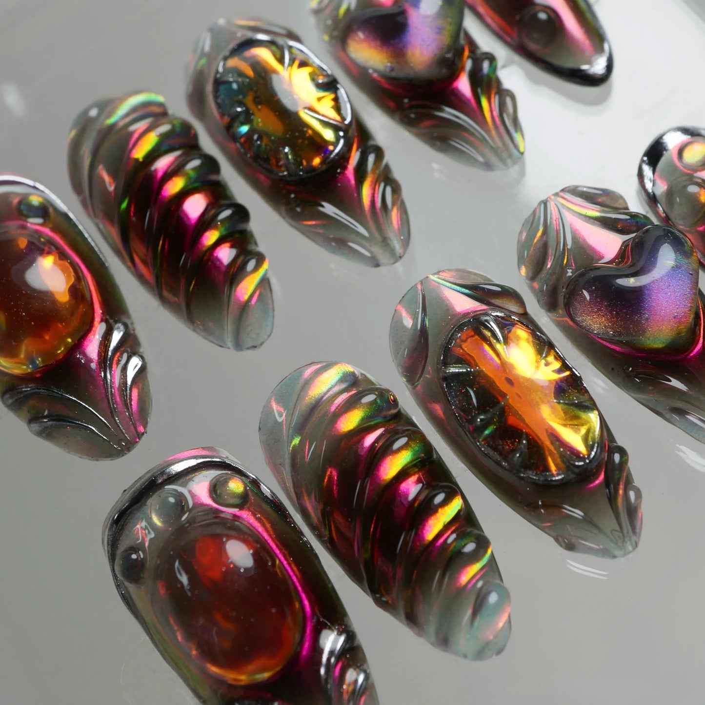 Donailsart press-on nails with black chrome armor style, fiery orange stones, and holographic finishes