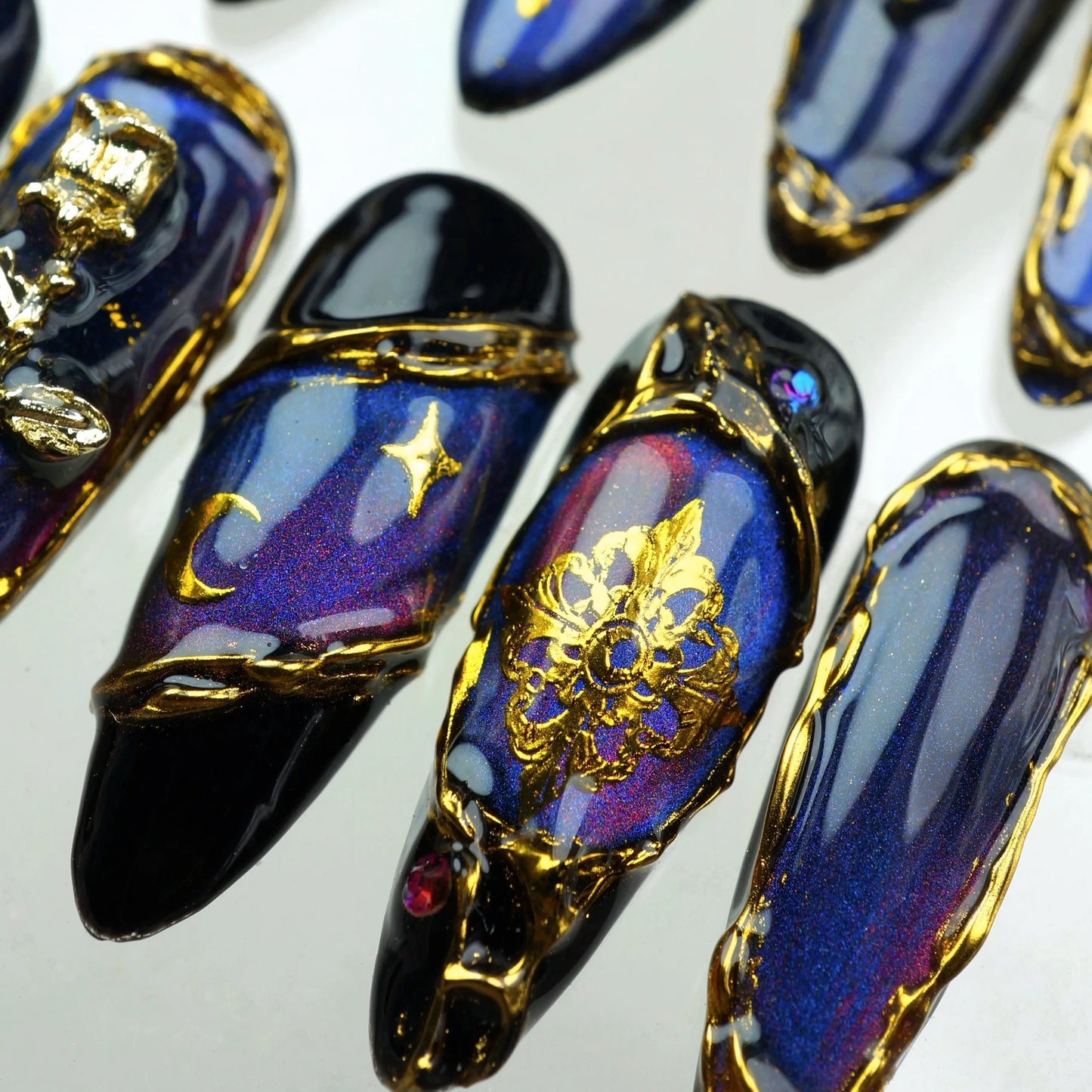 Mystical press-on nails with metallic shimmer, golden vintage motifs, crescent moons, and ruby-like stones