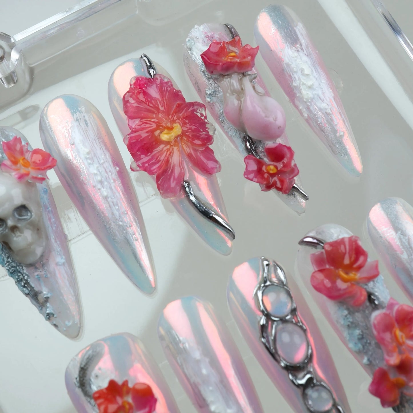 Statement summer nails art with reflective finishes, vibrant pink florals, and 3D gothic accents like bones and snakes