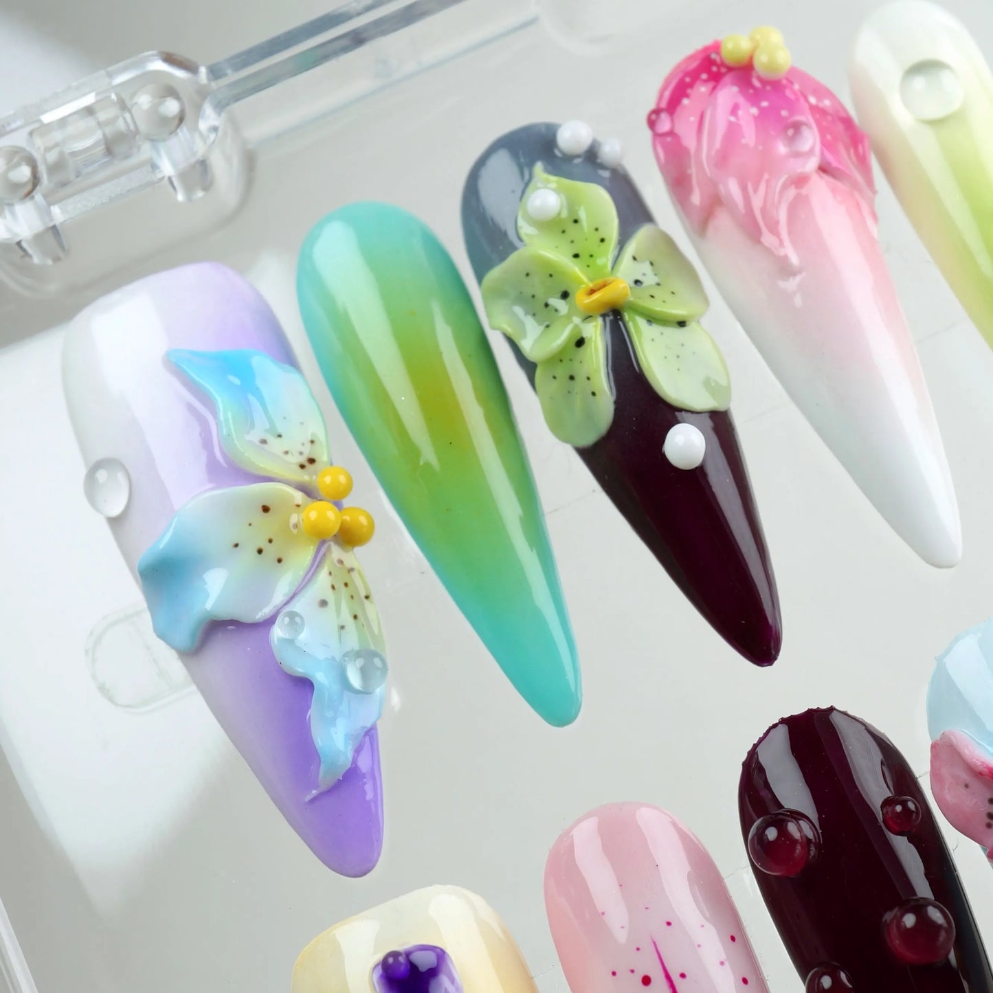 Floral-themed press-on nails by Donailsart with detailed hand-sculpted orchids and lilies in a rainbow palette