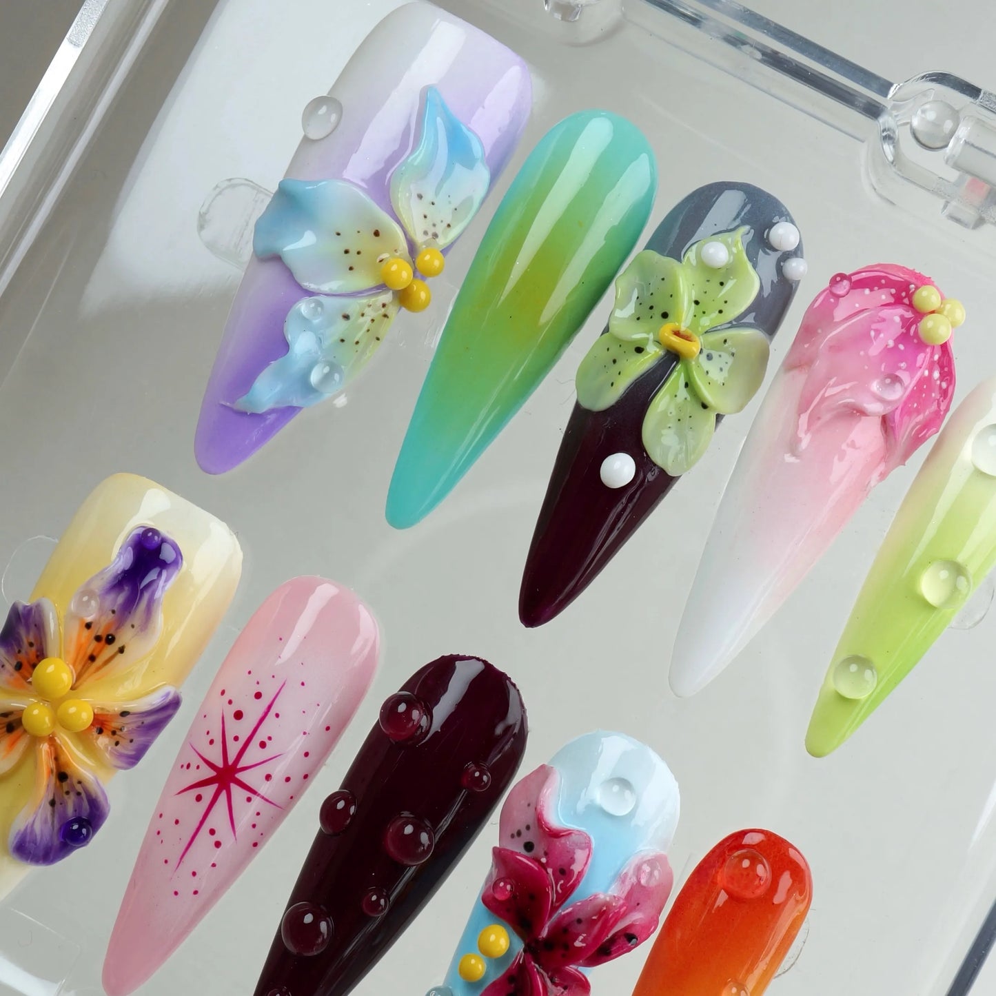 Pastel and jewel-toned press-on nails with intricate 3D petals, dot art, and water-like textures from Donailsart
