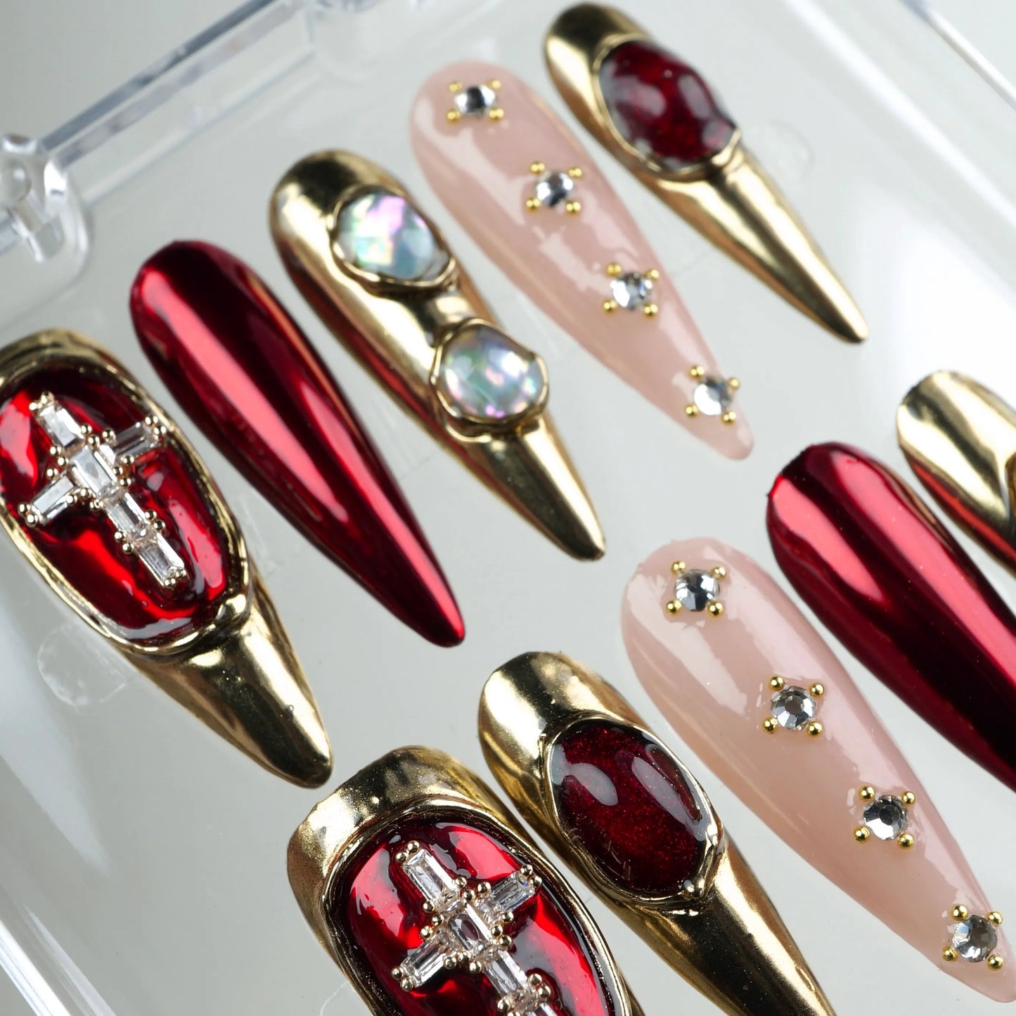 Donailsart press-on nails with red chrome, gold metal framing, and crystal cross accents
