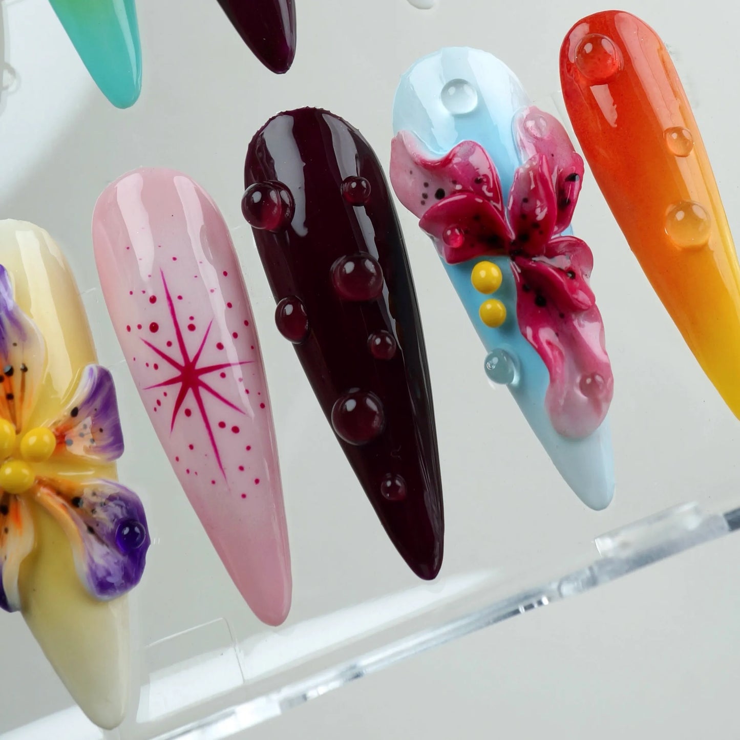 Colorful floral press-on nails from Donailsart with ombré gradients and 3D blossoms in bold summer shades