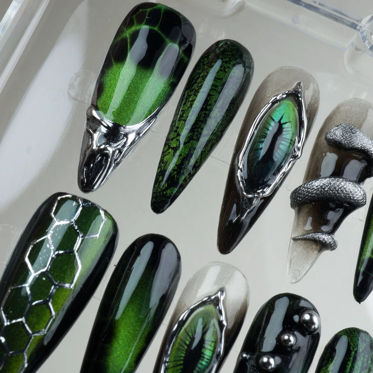 Fierce cat-eye nails design featuring chrome reptile eyes, metallic textures, and snake-inspired patterns