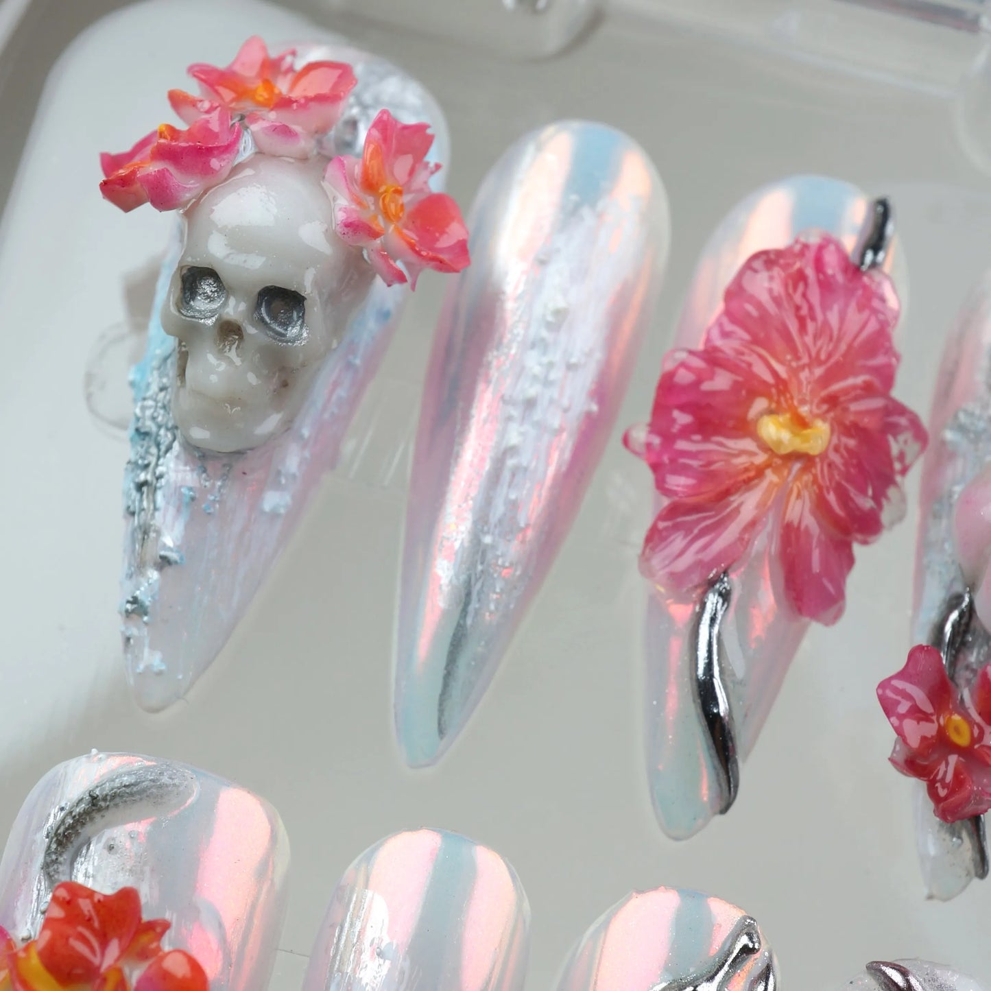 Fantasy-inspired summer nails art with pearl chrome base, sculpted flowers, mystical silver charms, and surreal motifs