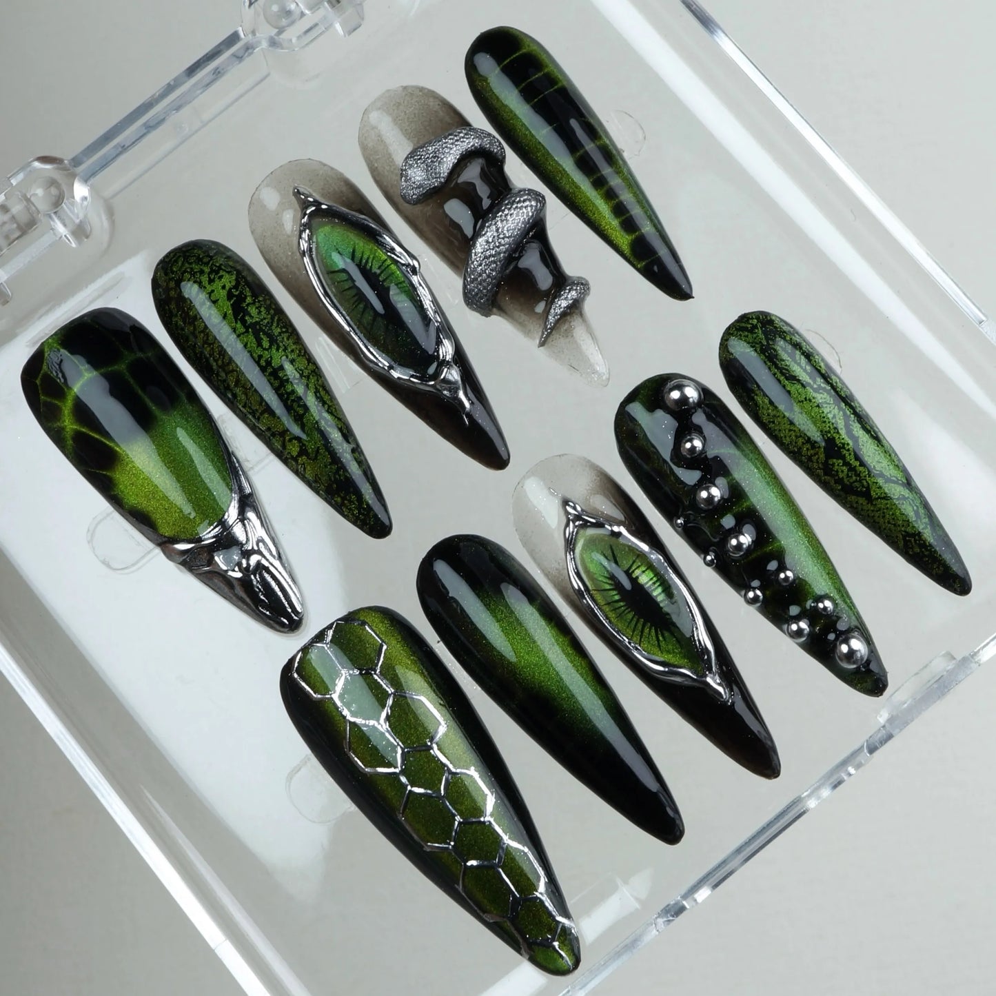 Fierce cat-eye nails design featuring chrome reptile eyes, metallic textures, and snake-inspired patterns
