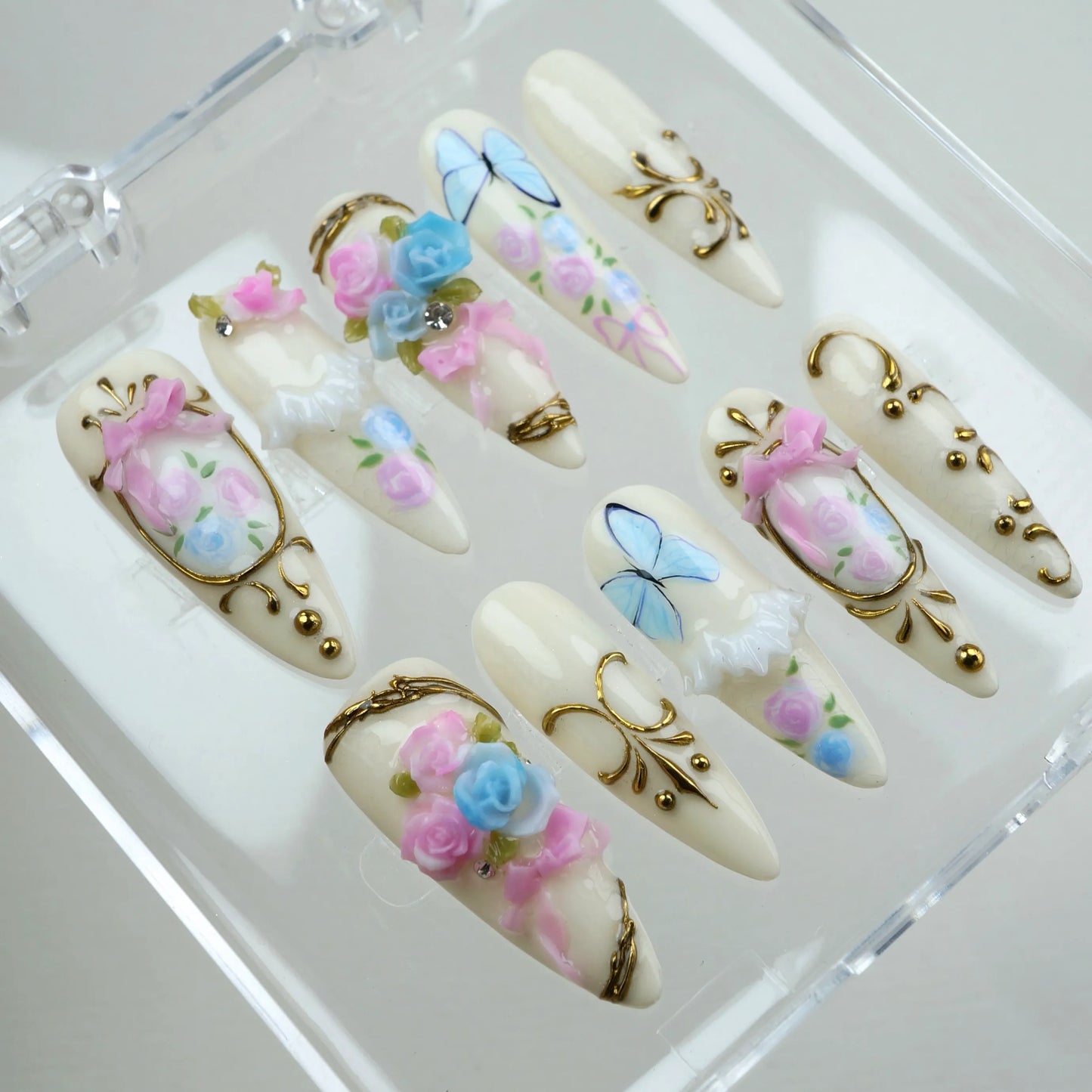 Regal birthday nails from Donailsart with hand-sculpted pink and blue roses, ribbon bows, and golden filigree