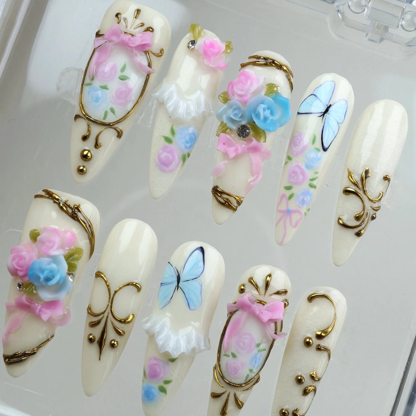 Donailsart birthday nails with pastel roses, blue butterflies, and ornate gold trims for a fairytale look