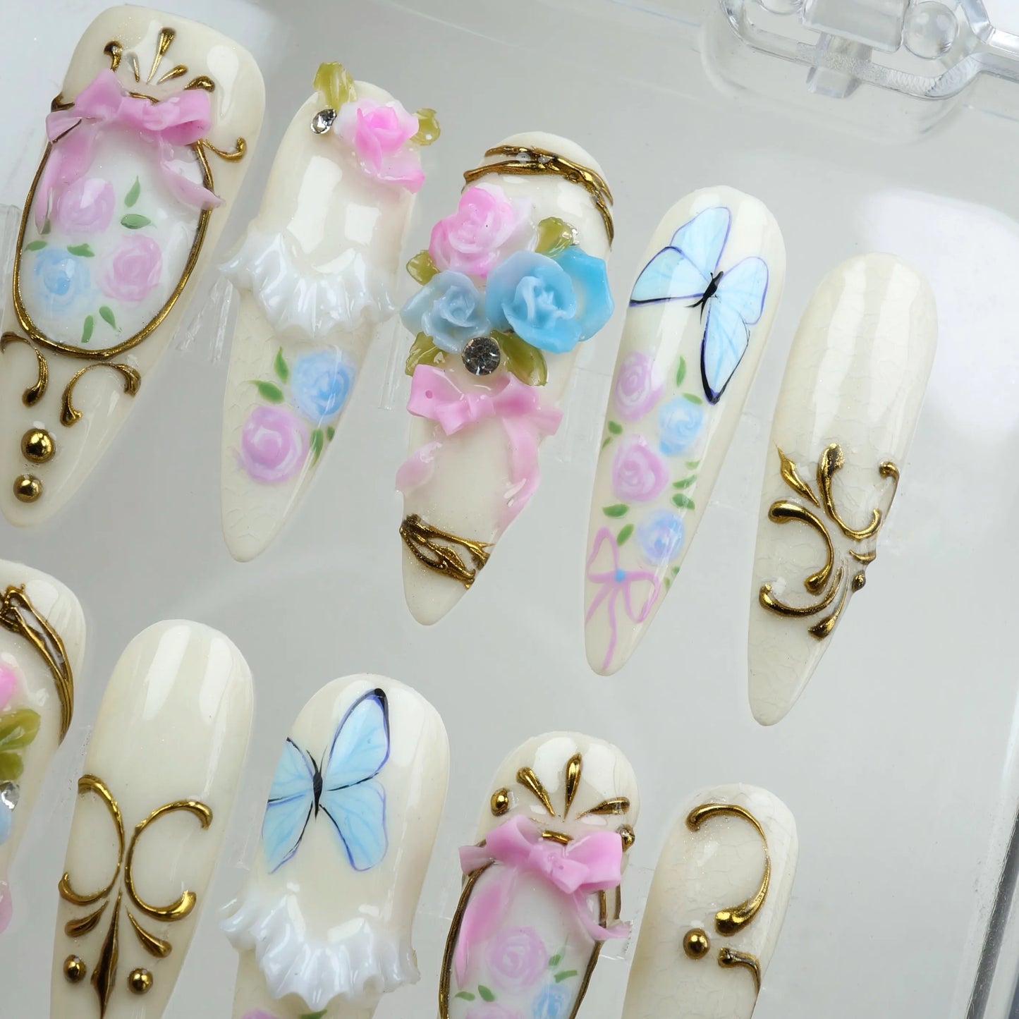 Donailsart birthday nails with pastel roses, blue butterflies, and ornate gold trims for a fairytale look