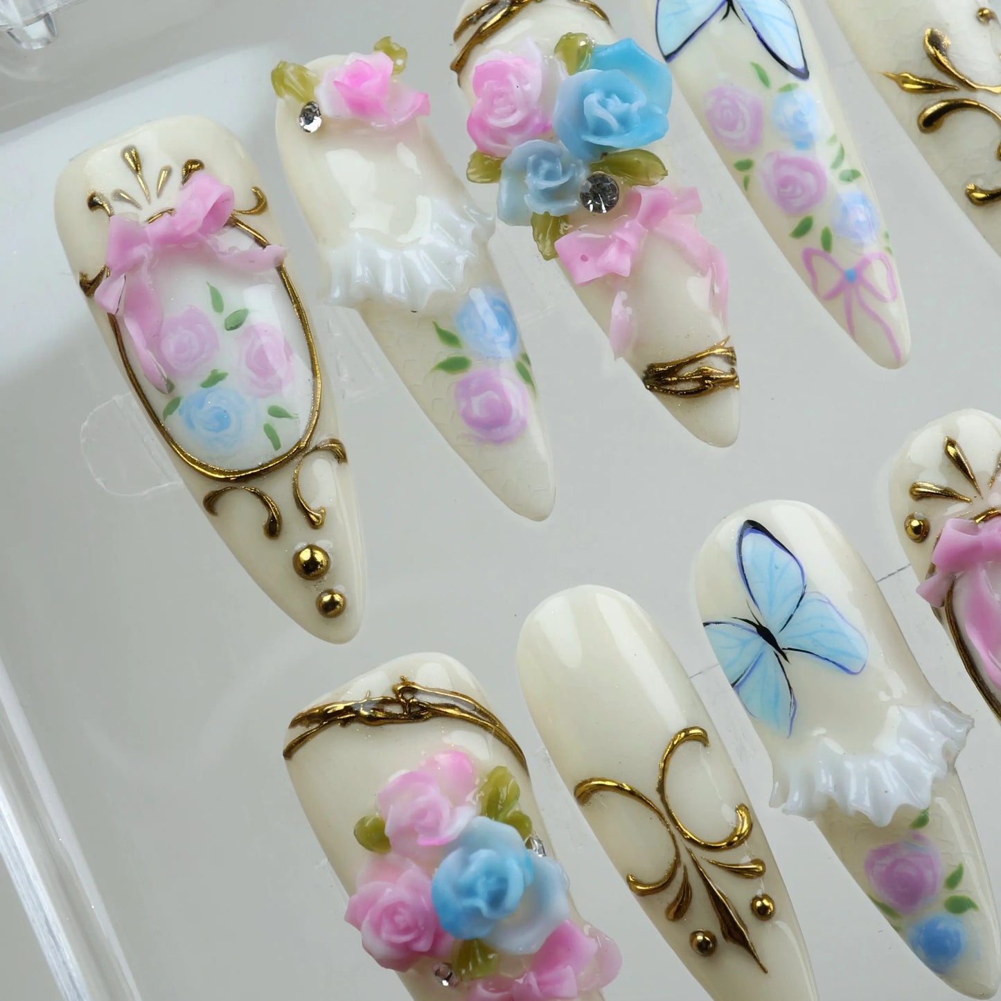 Charming birthday nails with soft ivory base, floral bouquets, butterflies, and princess-like gold details