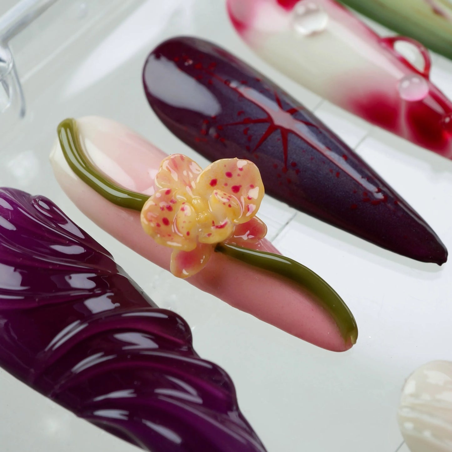 Creative flower design nails with a forest and fruit vibe, using deep red, green, and violet hues with organic textures