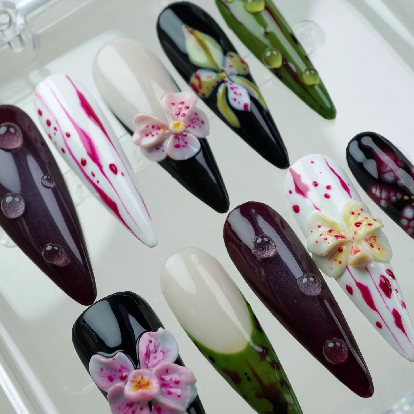 Unique flower design nails with a mix of natural and artistic patterns, including orchids, lilies, and glossy finishes