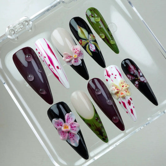 Artistic flower design nails blending white, black, and green bases with detailed hand-painted blossoms and water droplets