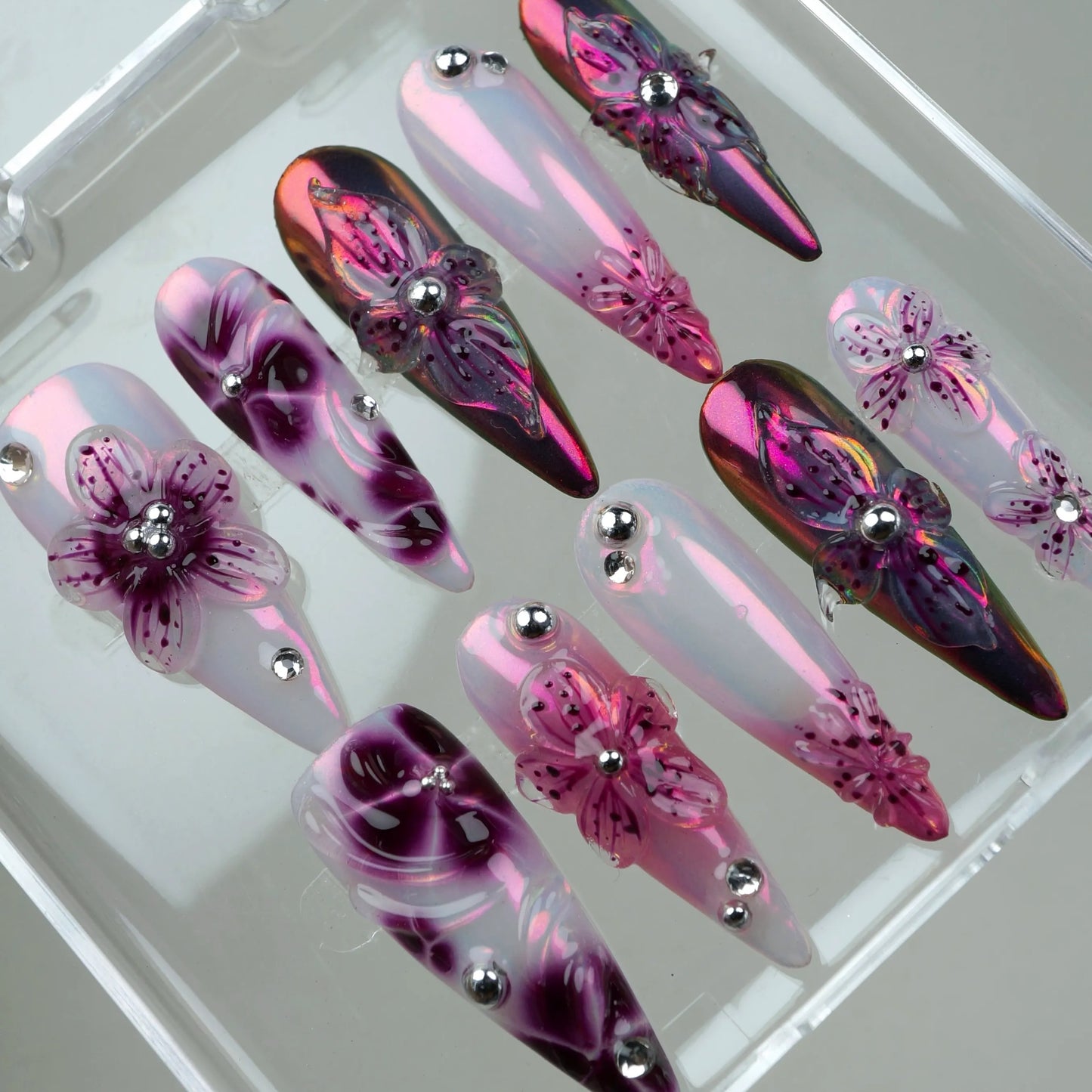 Sparkling flower design nails with layered petals, holographic shine, and silver bead accents for a chic vibe