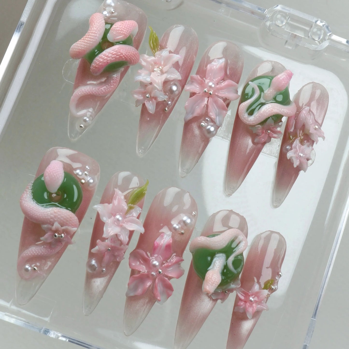 Creative flower design nails featuring jade-style orbs, intricate blossoms, and fantasy snake detailing
