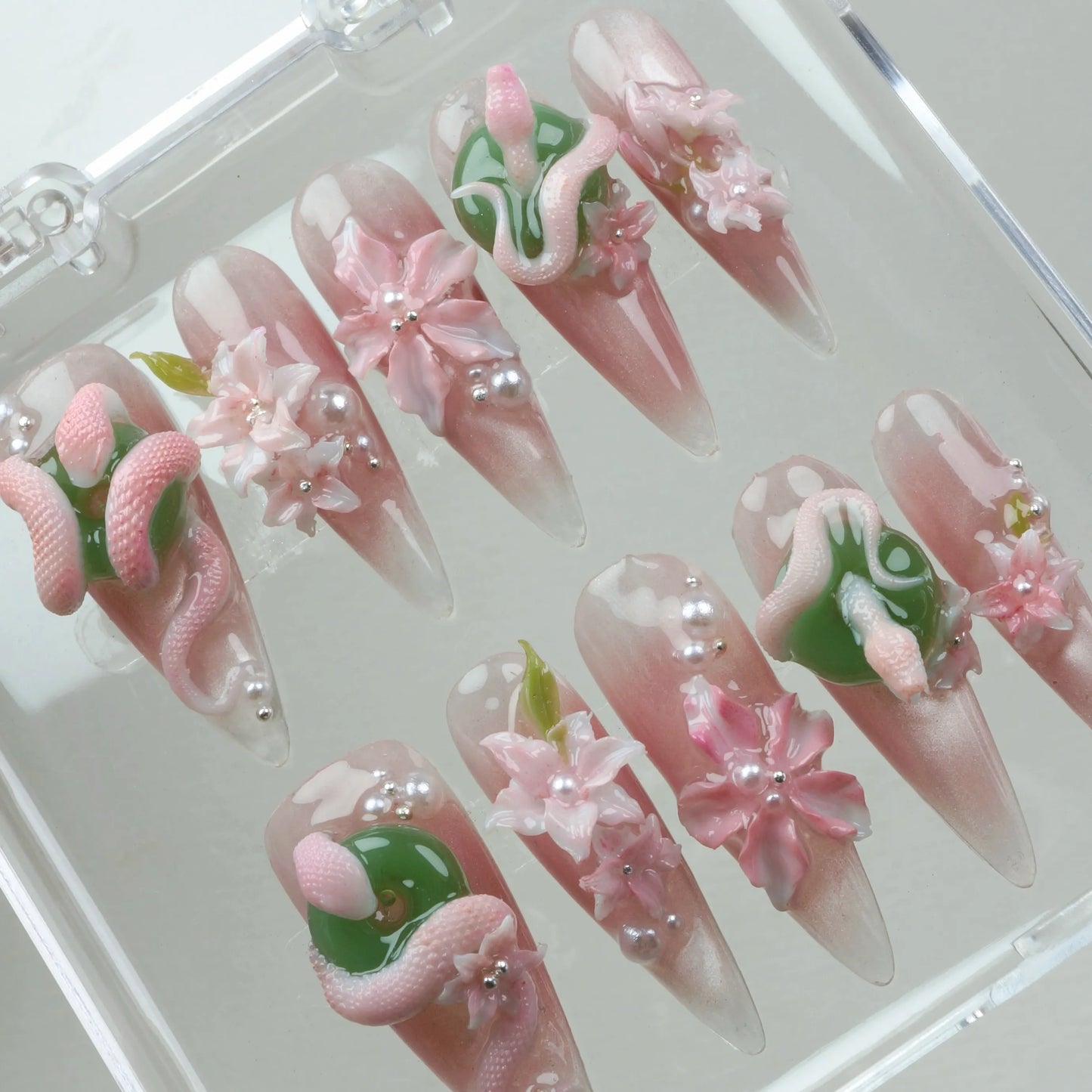 Fantasy-inspired flower design nails with pearl touches, blooming pink flowers, and textured snake shapes