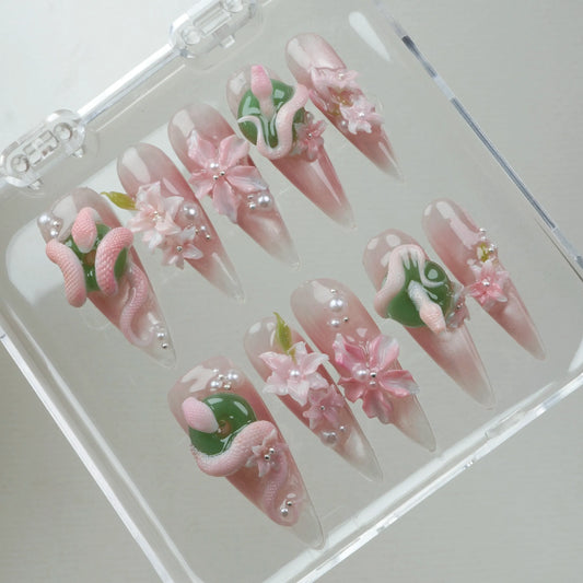Unique flower design nails with pastel serpents, glossy pink florals, and silver bead embellishments