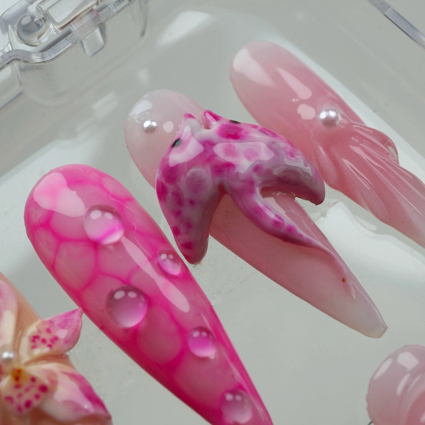 Soft and dreamy summer nails in shades of pink, decorated with sea life elements and orchid-style floral art.