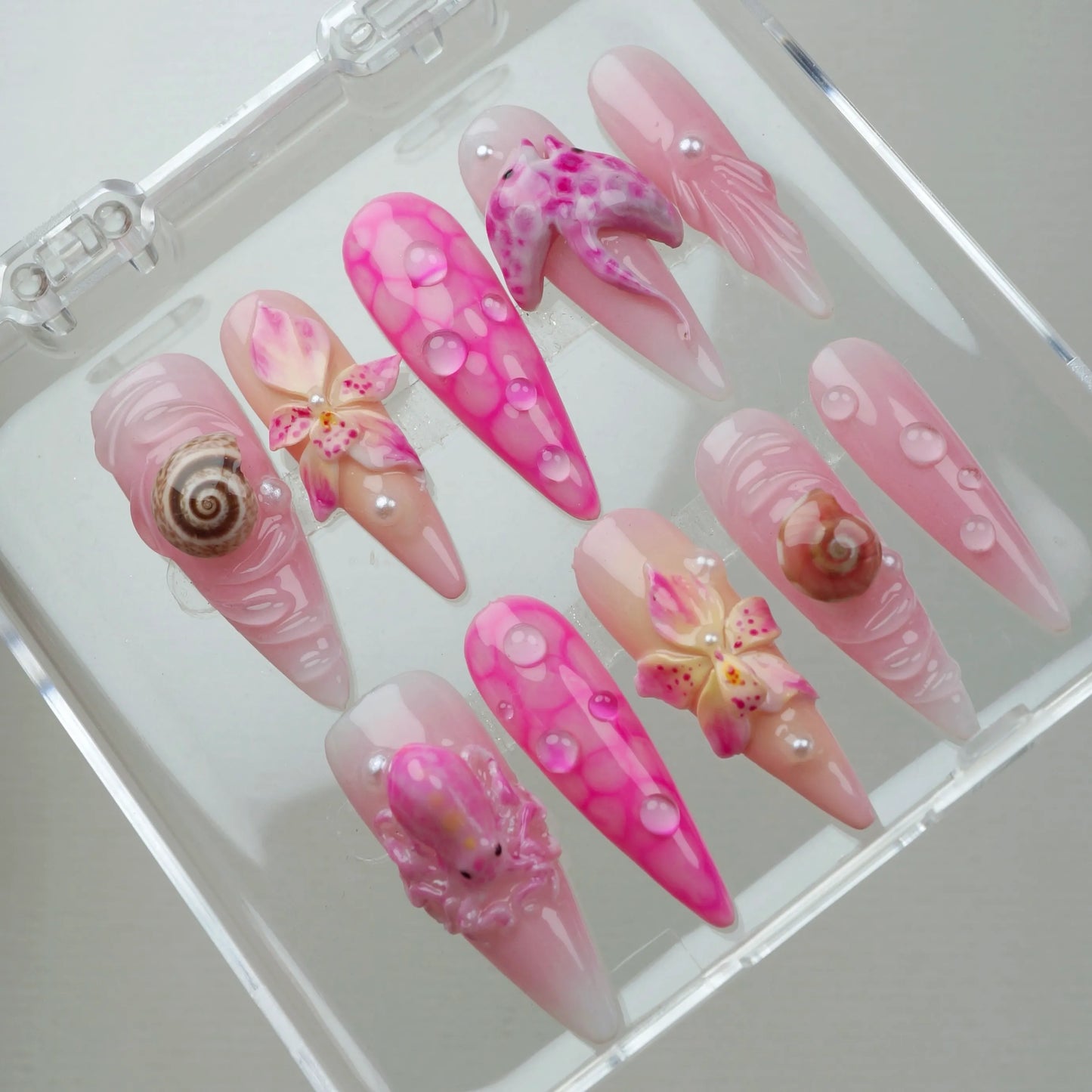 Pretty pink summer nails featuring ocean-inspired textures, realistic sea creatures, and tropical flower embellishments.