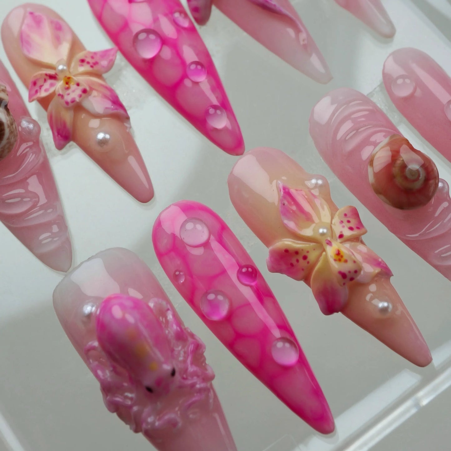 Romantic summer nails with ocean vibes, featuring 3D pink sea creatures, water droplets, and elegant flower motifs.