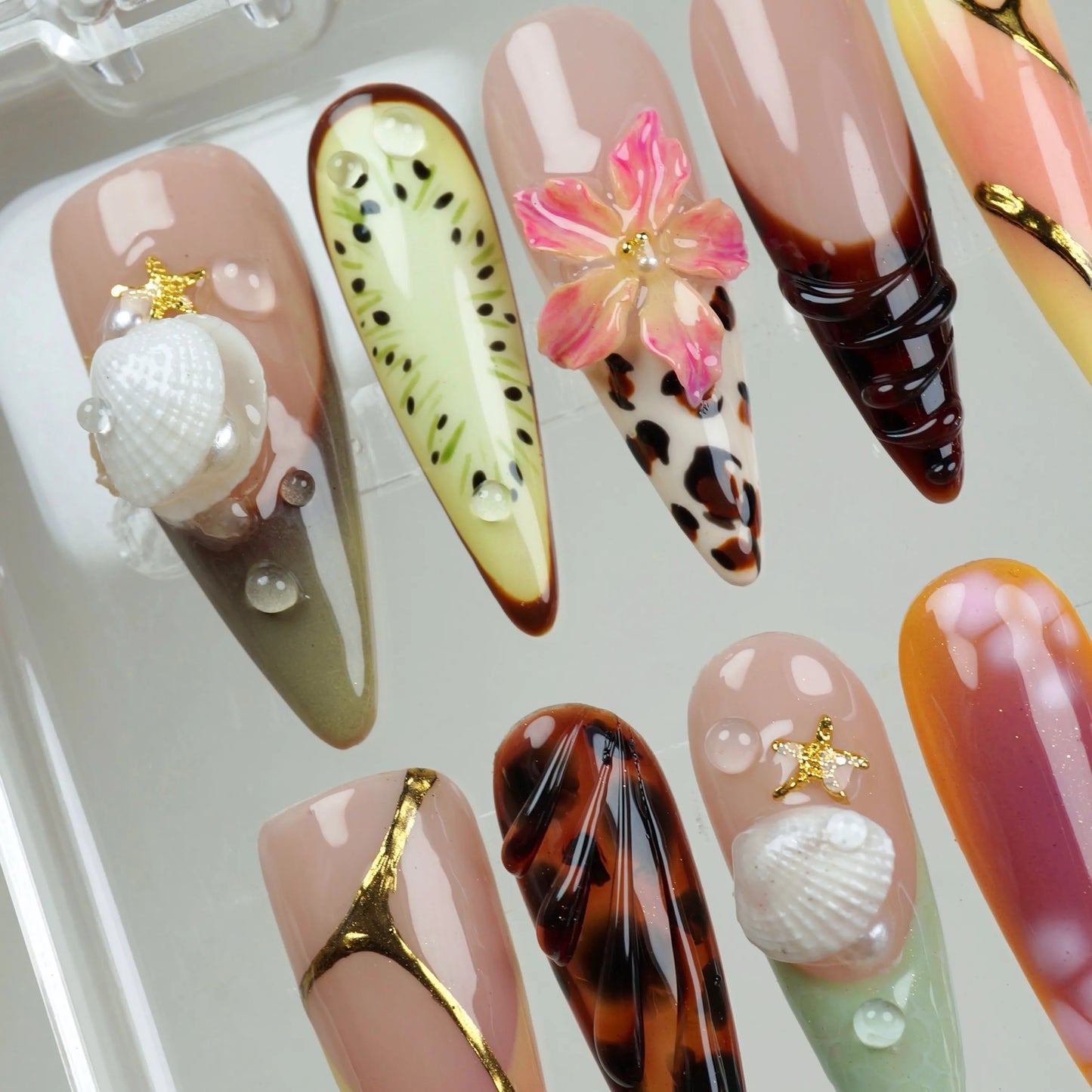 Tropical-themed summer nails showcasing a mix of designs like flowers, animal print, and seaside elements.